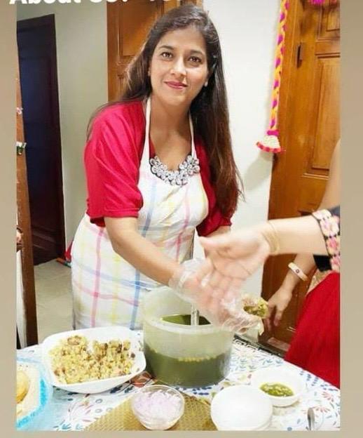 Aarti, founder of Aarti Home Food, smiling in her apron while serving homemade food